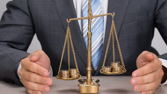 Businessman Protecting Justice Scale With Coins weighing whether you should reinvest dividends