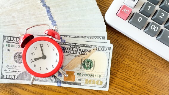 Alarm clock on dollar bills, short-term investment