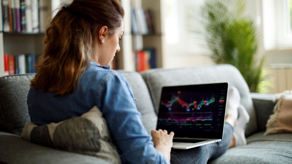 young-woman-sitting-on-couch-using-laptop-to-invest-in-stocks.jpg