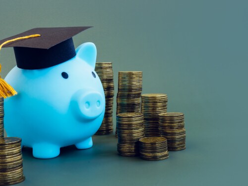 Saving for college with a 529 plan. Piggy bank with graduation cap. Stacks of coins.