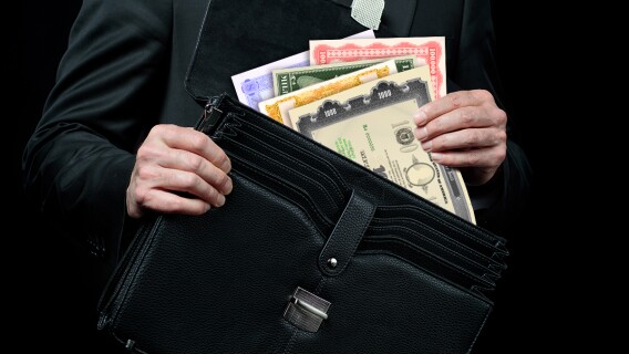 Person Putting Bonds in Briefcase 
