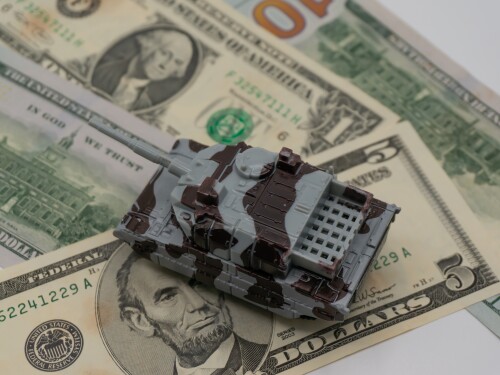 A miniature tank on U.S. dollar bills representing small-cap defense stocks.