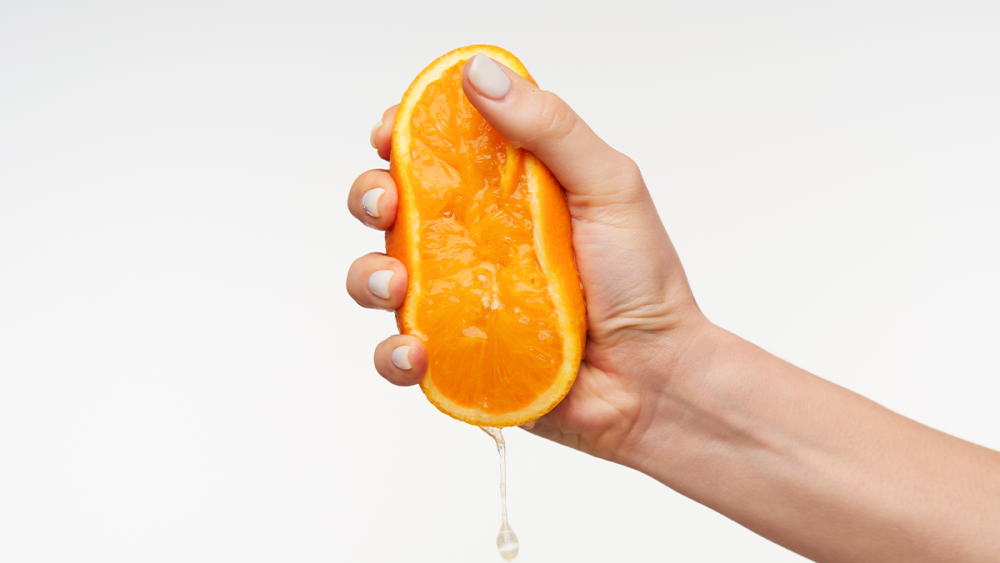 A Hand Squeezing an Orange 