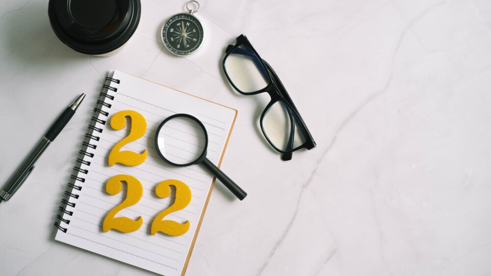 new year 2022 on desk 2022 goals with notebook, coffee cup, magnifying glass and glasses on wooden background, growth investing lessons, goals, plans, strategies