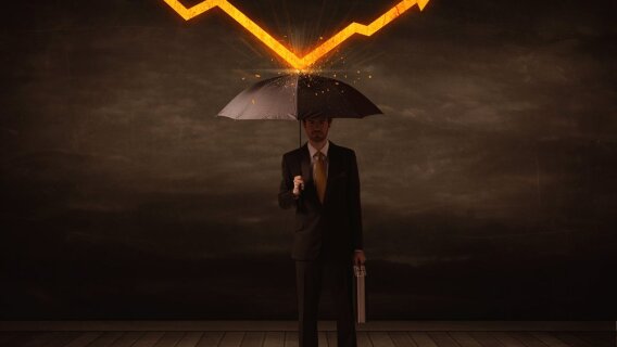 Businessman standing with umbrella keeping falling orange arrow off him signifying the protection provided by an all-weather income stock
