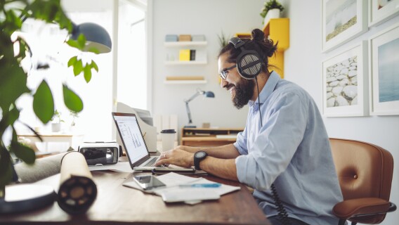 Investor sitting at laptop wearing headphones listening to a value investing podcast