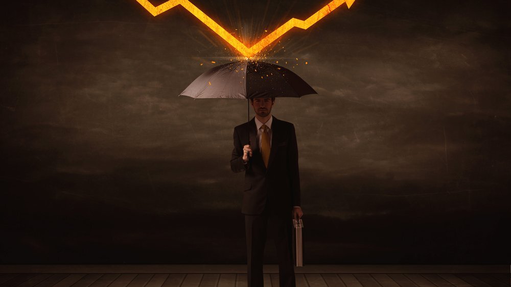 Businessman standing with umbrella keeping falling orange arrow off him signifying the protection provided by an all-weather income stock