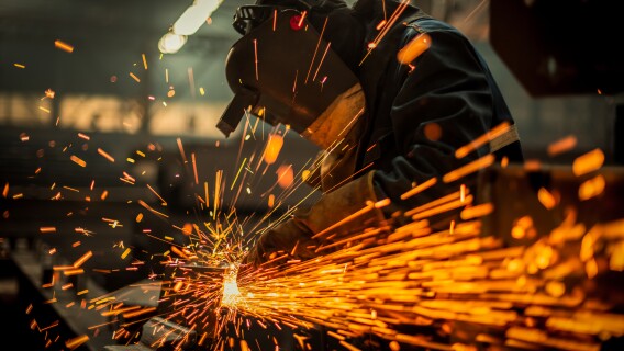 Metal worker using a grinder representing U.S. steel production, manufacturing